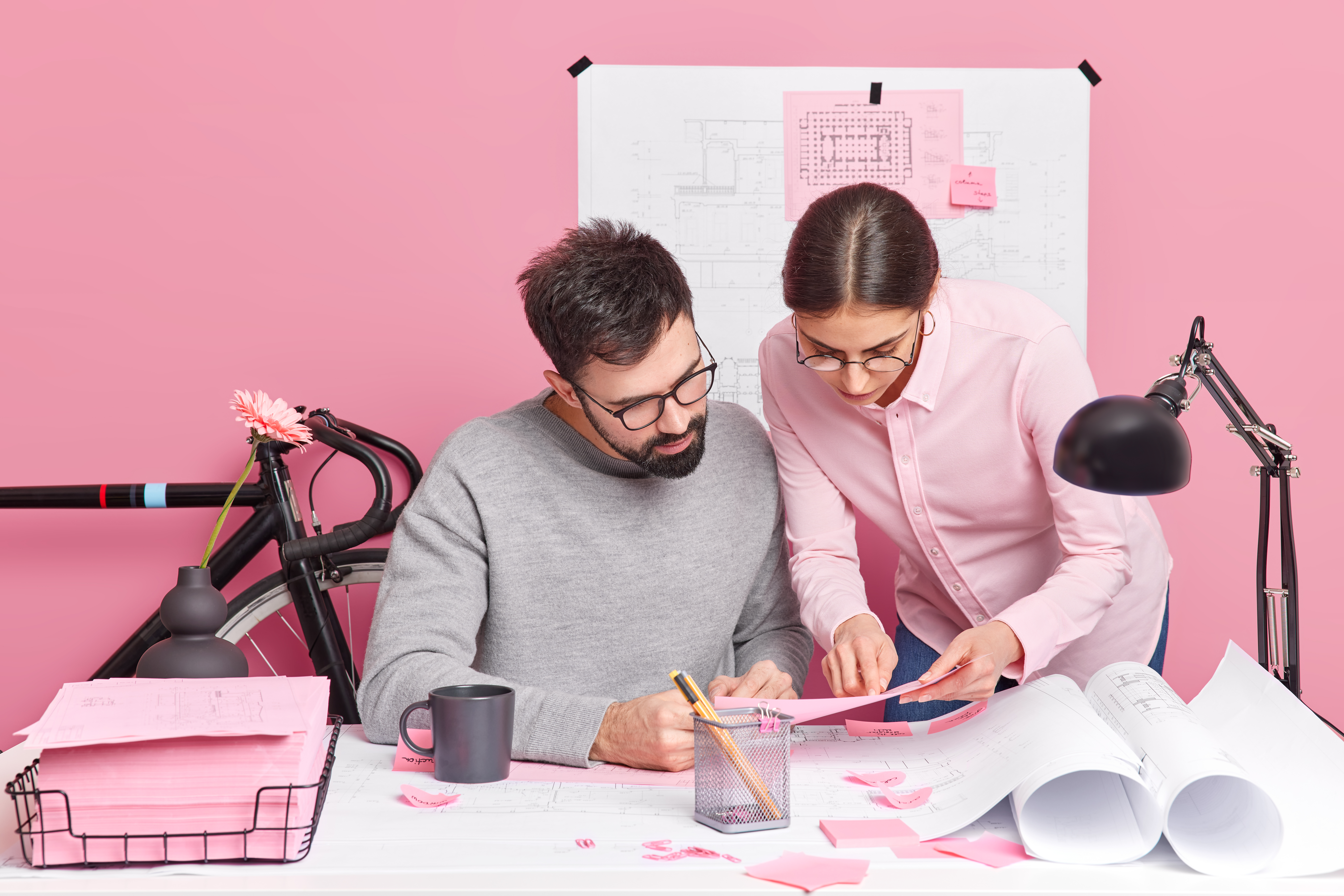 Colourful pink office with man and woman reviewing documents